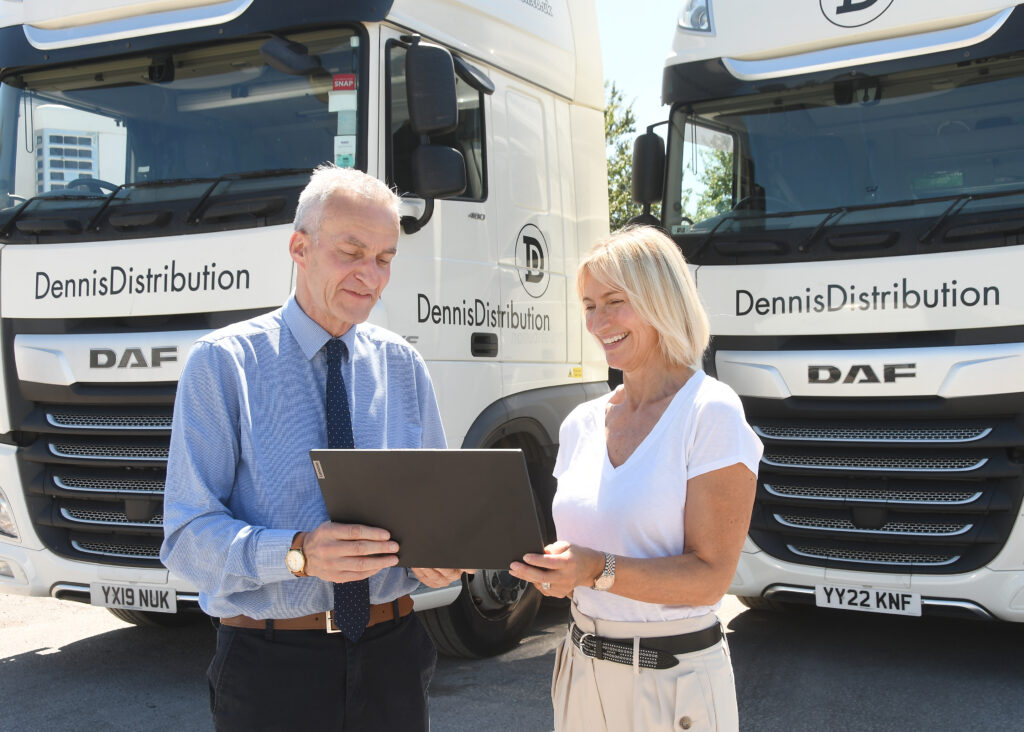 Dennis Distribution staff looking at a check list next to their HGV fleet