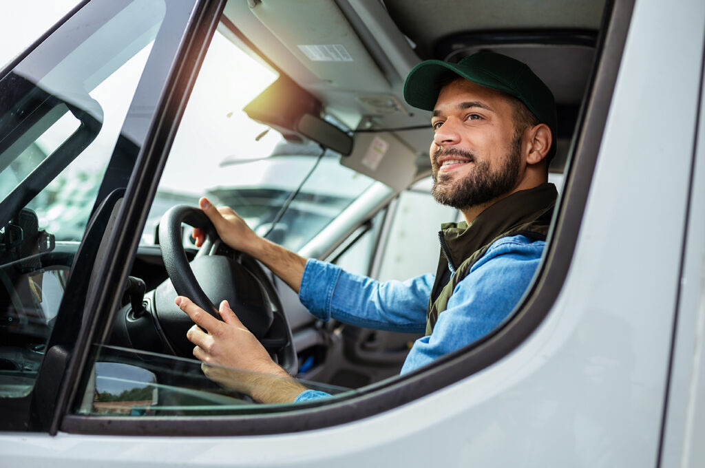 a HGV driver looking out the window of a lorry and smiling